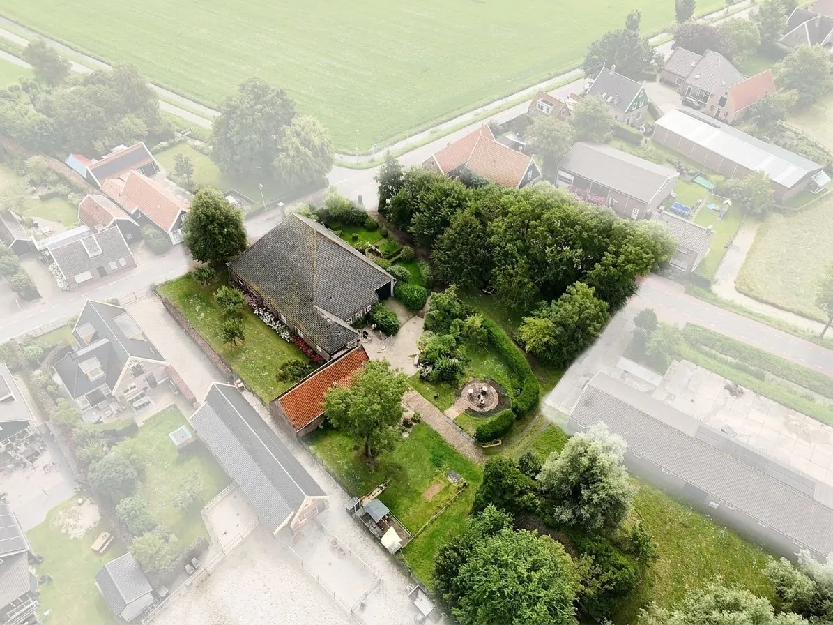 Achterzijde van het erf van Hoeve Veelust, met de stolp tussen de weilanden en het lint van Aartswoud.
